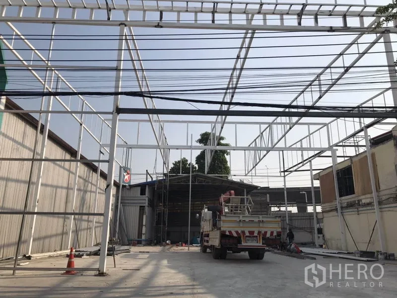 Warehouse for rent in Bang Na, Bangkok - Outdoor loading yard with a new steel canopy frame under construction and truck access.