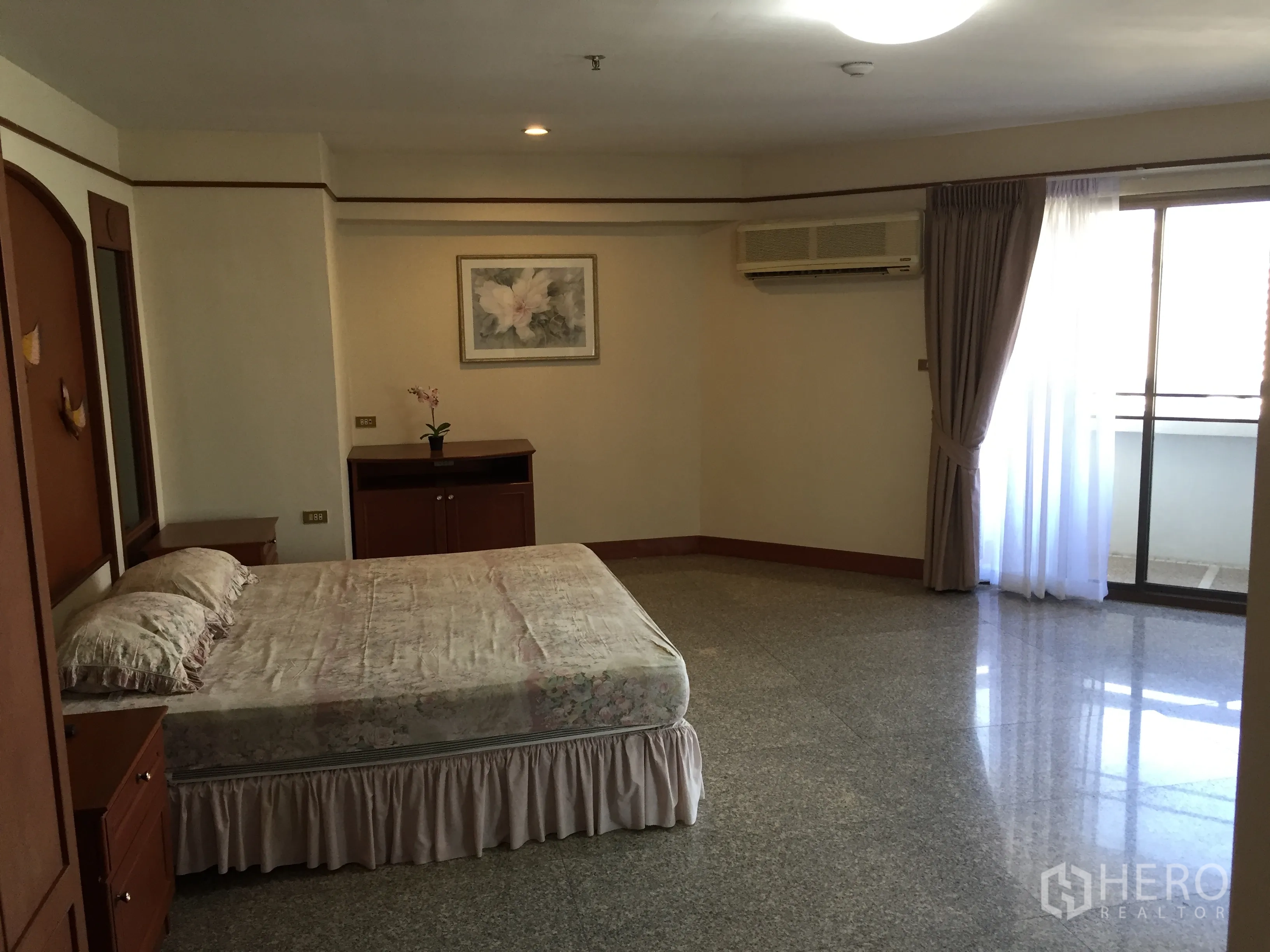 Condominium for rent in Watthana, Bangkok - King-size master bedroom with sliding door to balcony, curtains, wall A/C and built-in cabinet in a Bangkok condo.