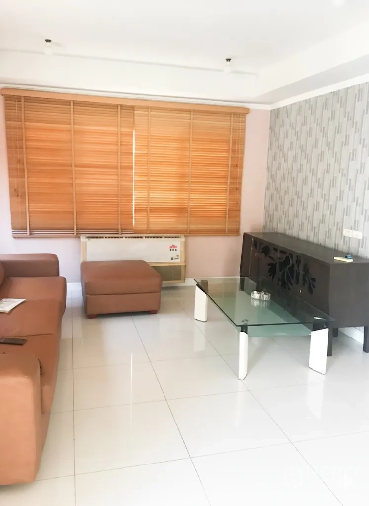 Detached House for rent in Lat Krabang, Bangkok - Living room with leather sofa, glass coffee table, white tiled floor and wooden blinds.