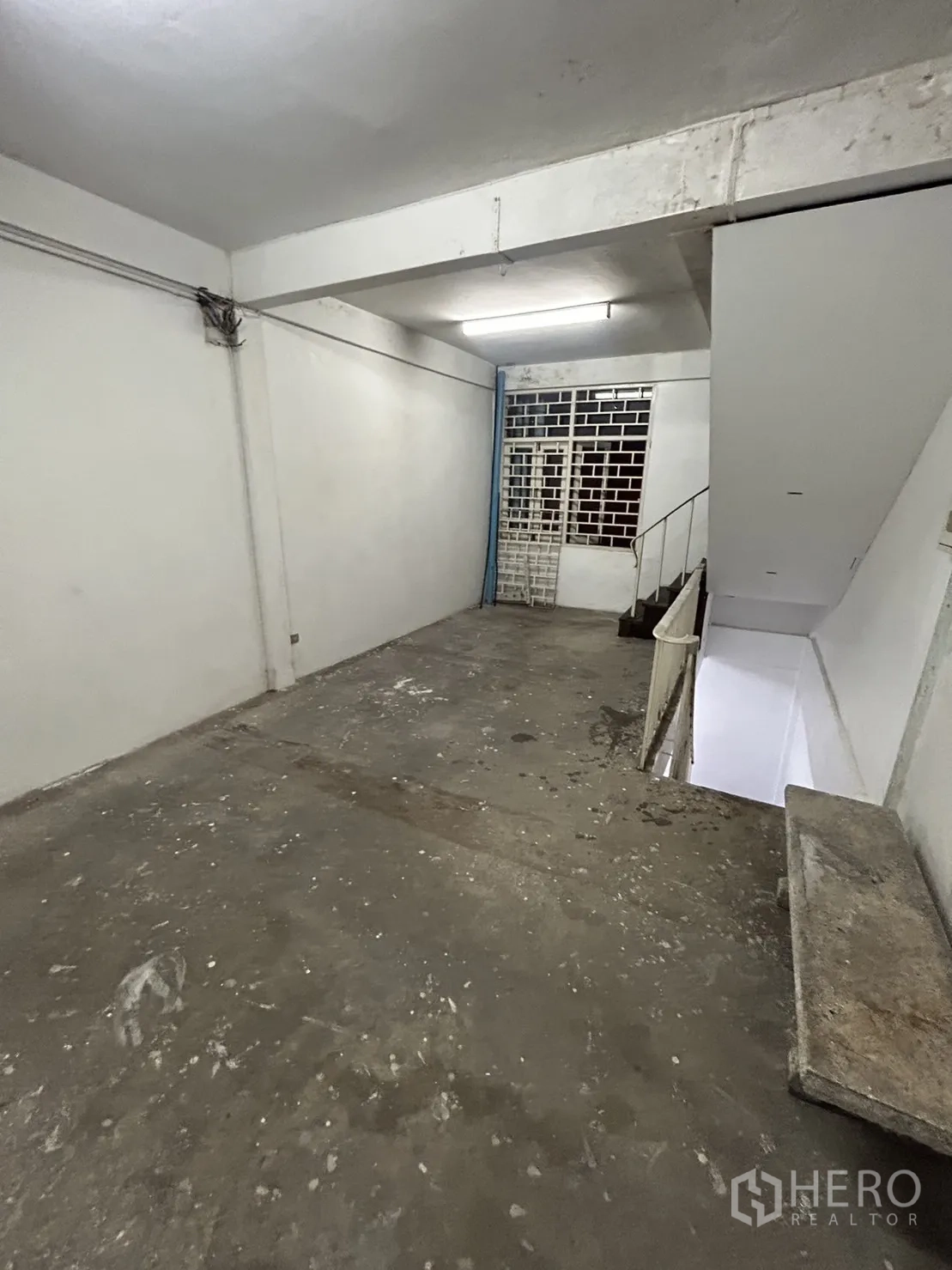 Shophouse for rent in Khlong Toei, Bangkok - Concrete storage area with metal gate and stairs leading down.