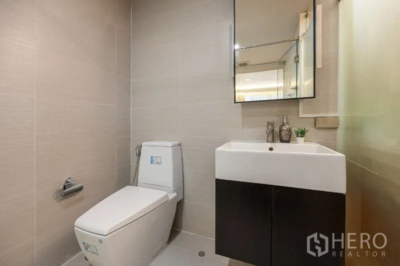 Condominium for sale - Compact guest bathroom with toilet, vanity sink and wall mirror.