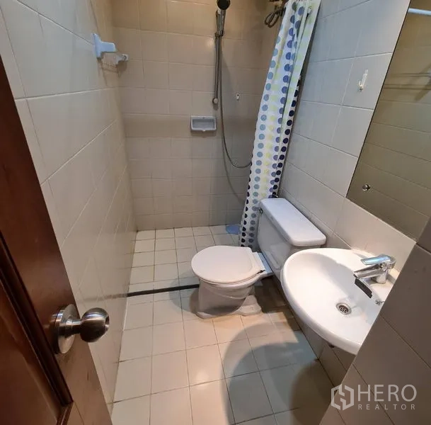 Condominium for rent or sale in Watthana, Bangkok - Second bathroom with walk-in shower, toilet and basin in neutral tiles.