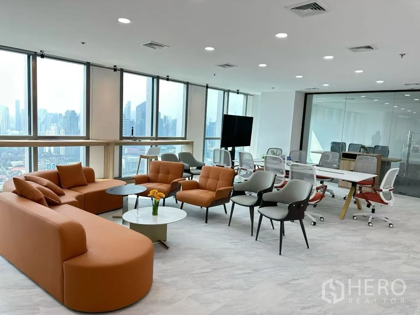 Office Space for rent in Huai Khwang, Bangkok - Modern lounge and meeting area with orange sofas, conference table and panoramic city windows.