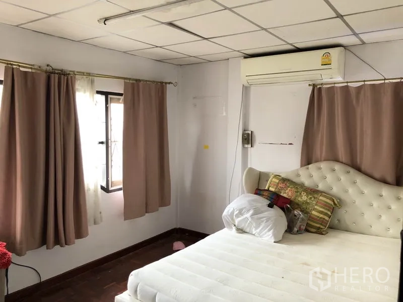 บ้าน ขายในPak Kret, Nonthaburi - ห้องนอนหลักมีหน้าต่างหลายบาน ผ้าม่าน เครื่องปรับอากาศ และหัวเตียงบุกำมะหยี่
