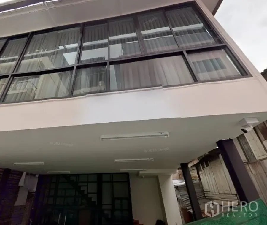 Home Office for rent in Yan Nawa, Bangkok - Modern home office exterior in Yan Nawa, Bangkok featuring large glass windows, exterior lighting, and a covered parking area under the building.
