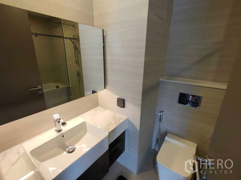 Condominium for rent in Watthana, Bangkok - Modern bathroom vanity with a large mirror, sink, and built-in storage.