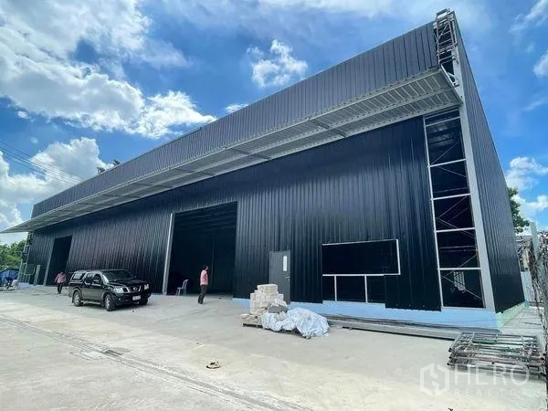 คลังสินค้า ให้เช่าในPak Kret, Nonthaburi - ด้านหน้าโกดังเมทัลชีทสีดำ หลังคายื่นสูง ทางขึ้นลงกว้าง ในอำเภอปากเกร็ด นนทบุรี