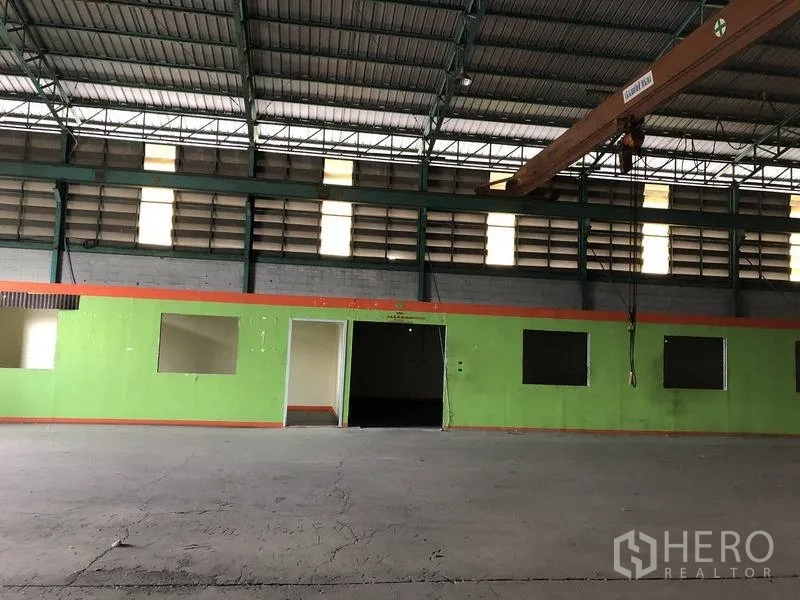 Warehouse for rent in Samut Prakan - Warehouse interior showing green office rooms, multiple windows, and broad loading space.
