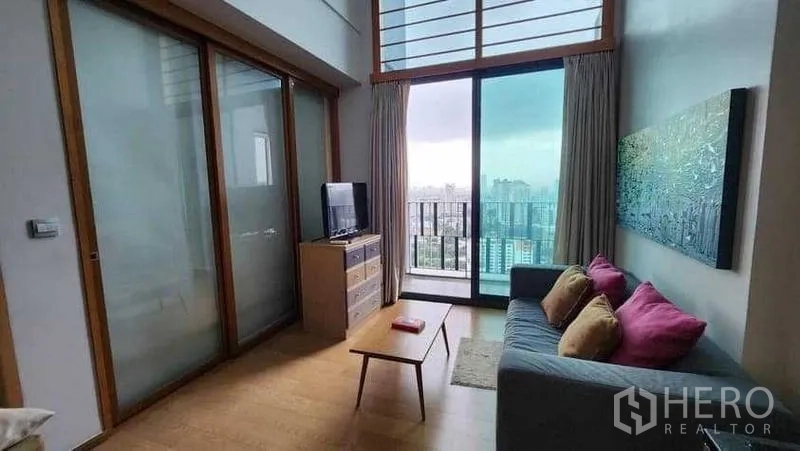 Condominium for rent in Khlong Toei, Bangkok - Living room with sliding glass partition and city-view balcony.