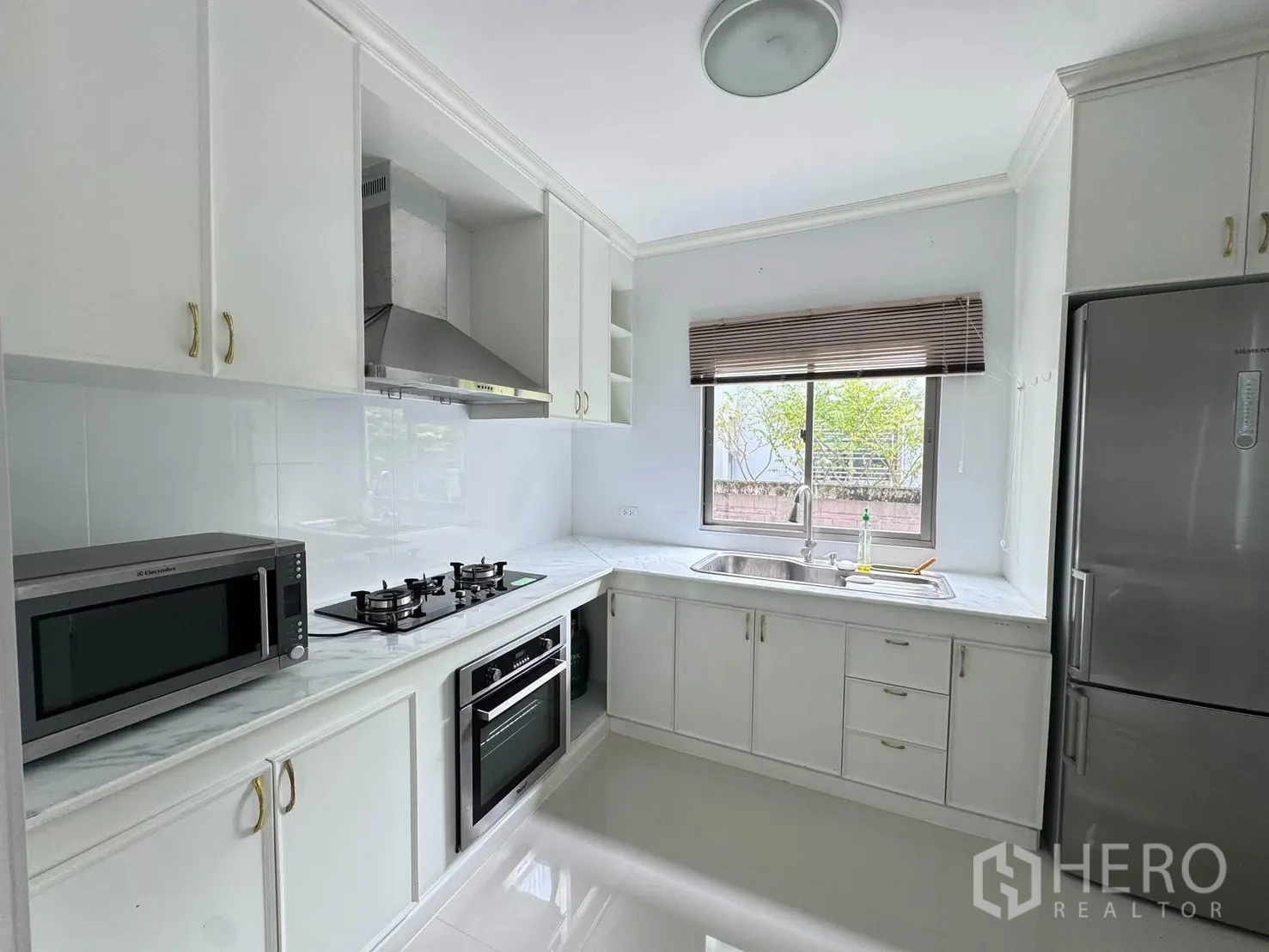 半独立式住宅 for rent or sale in Suan Luang, Bangkok - 另一角度的白色整体厨房，配燃气炉、烤箱、微波炉与冰箱。