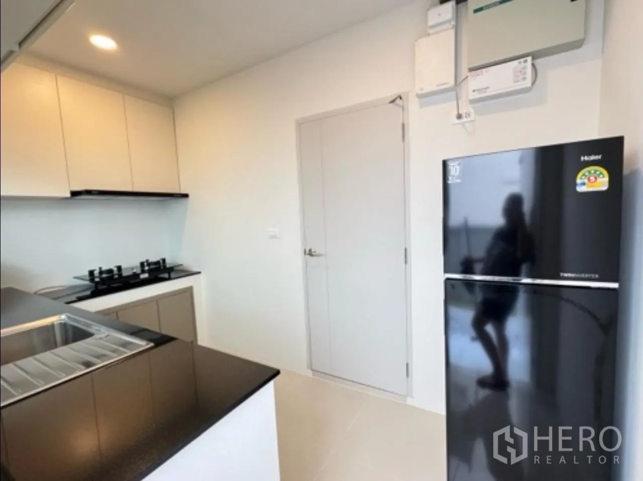 Detached House for rent in Bang Phli, Samut Prakan - Kitchen view showing refrigerator, door and overhead cabinetry.