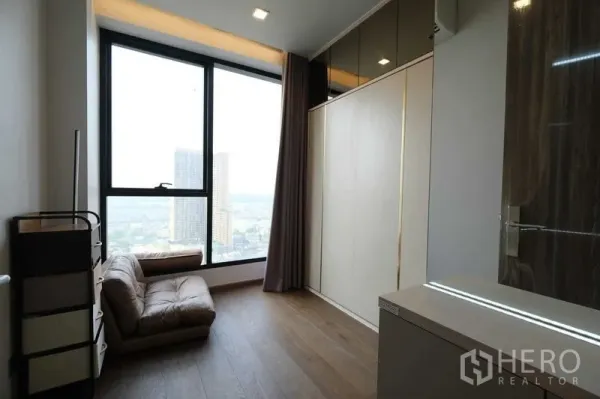 Condominium for rent in Khlong Toei, Bangkok - Bright bedroom with floor-to-ceiling window, built-in wardrobe, and city view.