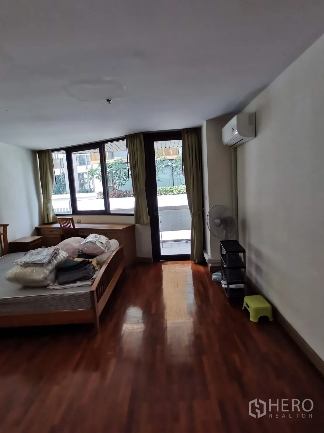 公寓 出租在Pathum Wan, Bangkok - 卧室一角可见通往露台的门、窗边书桌与壁挂空调。