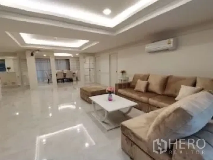 Apartment for rent in Watthana, Bangkok - Open-plan living area with a beige sectional sofa and coffee table, view toward the dining space.