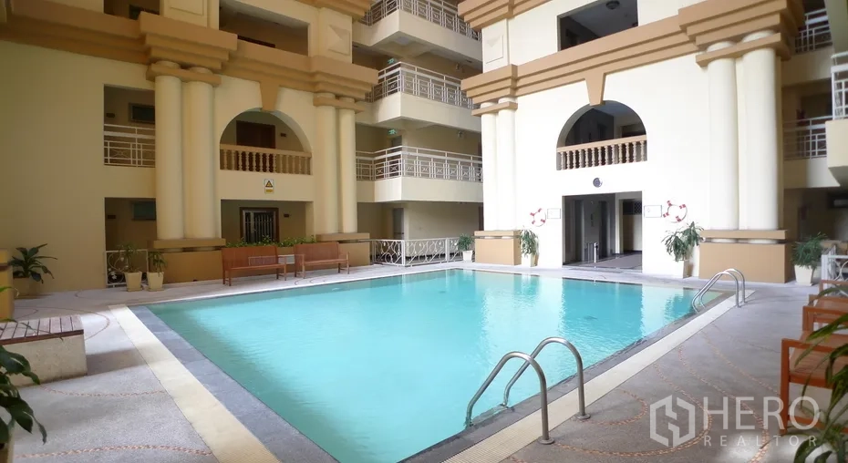 Condominium for rent or sale in Watthana, Bangkok - Indoor condominium swimming pool with classical columns and surrounding balconies.