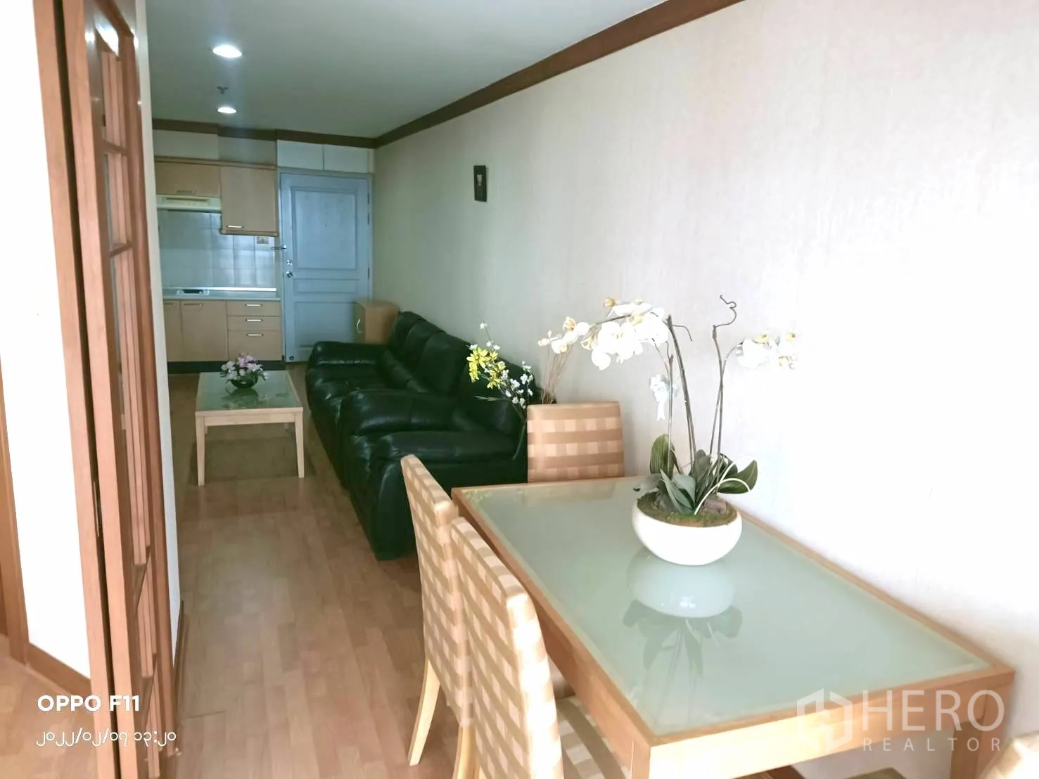 Condominium for rent in Khlong Toei, Bangkok - View from the dining area to a compact kitchen and long living room with sofa.