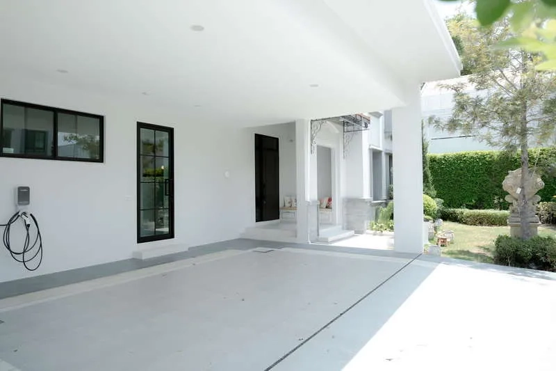 Detached House for rent or sale in Saphan Sung, Bangkok - Covered carport with EV charger and walkway to a landscaped garden.