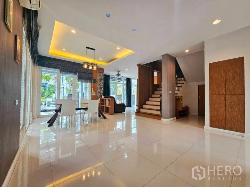Detached House for rent in Chatuchak, Bangkok - Spacious open-plan living and dining area with staircase and glossy tiled floors.