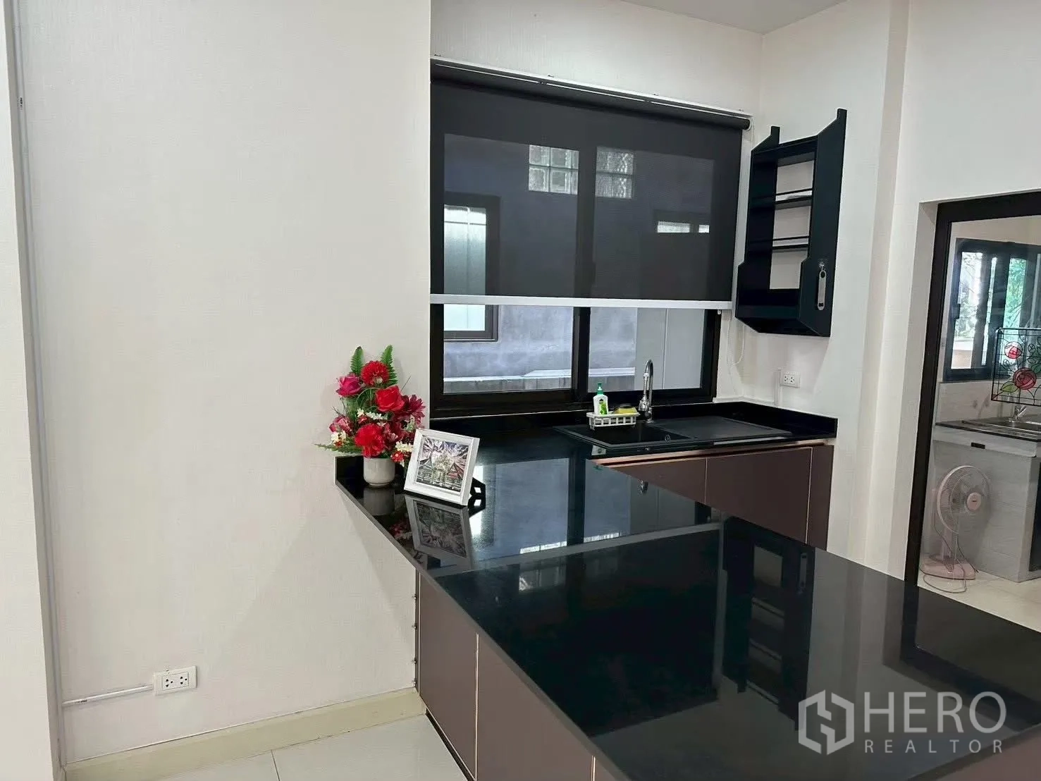 Detached House for rent in Bang Phli, Samut Prakan - Open kitchen with black stone countertops, sink under a window and corner shelves.
