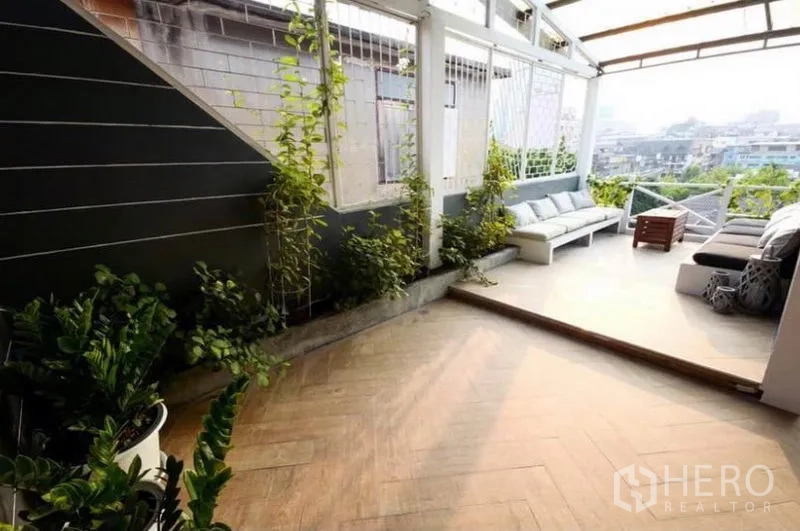 Townhouse for rent in Ratchathewi, Bangkok - Rooftop terrace with sofas, greenery and open city views.