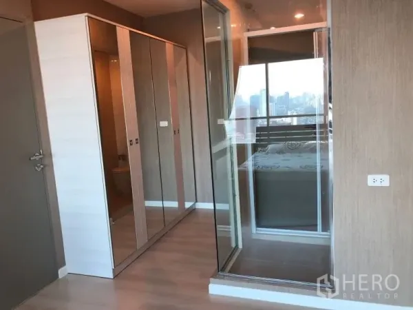 Condominium for rent or sale in Huai Khwang, Bangkok - Walk-in area with mirrored wardrobes and a glass partition next to the bedroom.