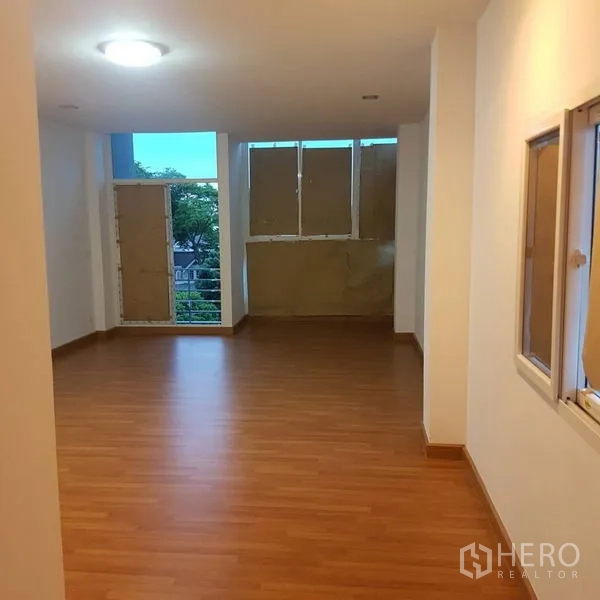 Home Office for sale in Lat Phrao, Bangkok - Empty office floor with warm wood laminate flooring and natural light from windows.