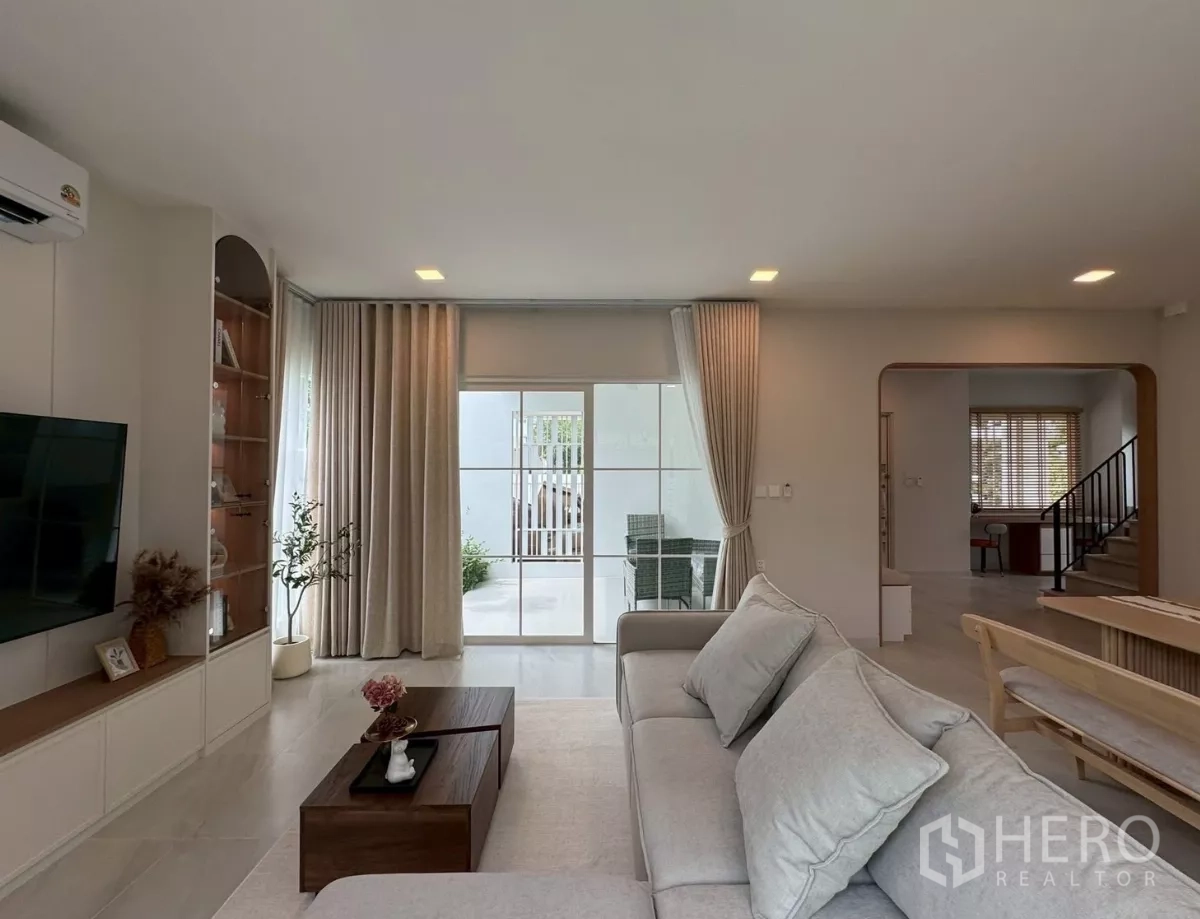 Detached House for rent in Bang Phli, Samut Prakan - Bright living area with sofa facing TV, sliding doors to patio and staircase nearby