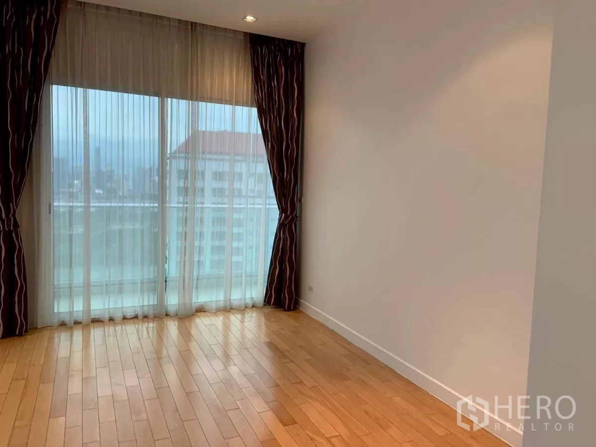 Condominium for rent in Khlong Toei, Bangkok - Master bedroom with balcony doors, curtains and skyline view.