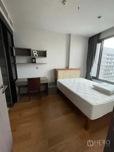 Condominium for rent in Khlong Toei, Bangkok - Bright bedroom with large window, desk and shelves, wood flooring and city outlook.