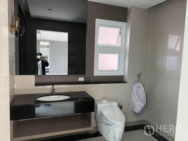 Detached House for sale in Yan Nawa, Bangkok - Modern bathroom with large mirror, sleek vanity, toilet and window.