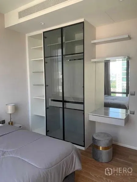 公寓 出租在Pathum Wan, Bangkok - 卧室内的玻璃推拉衣柜、开放式搁架与梳妆台，现代简约风。