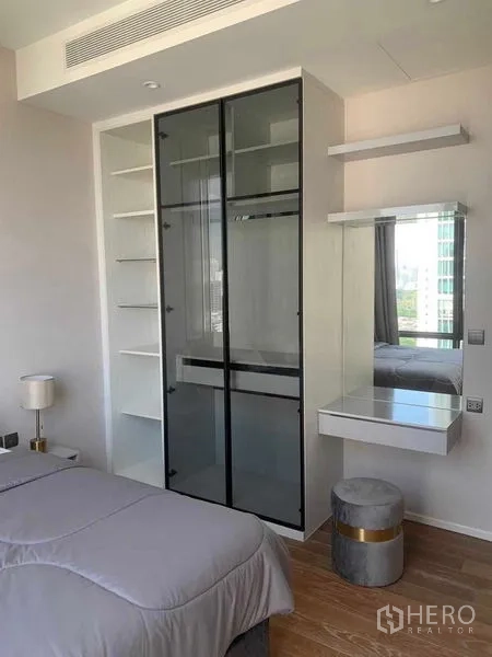 公寓 出租在Pathum Wan, Bangkok - 卧室内的玻璃推拉衣柜、开放式搁架与梳妆台，现代简约风。