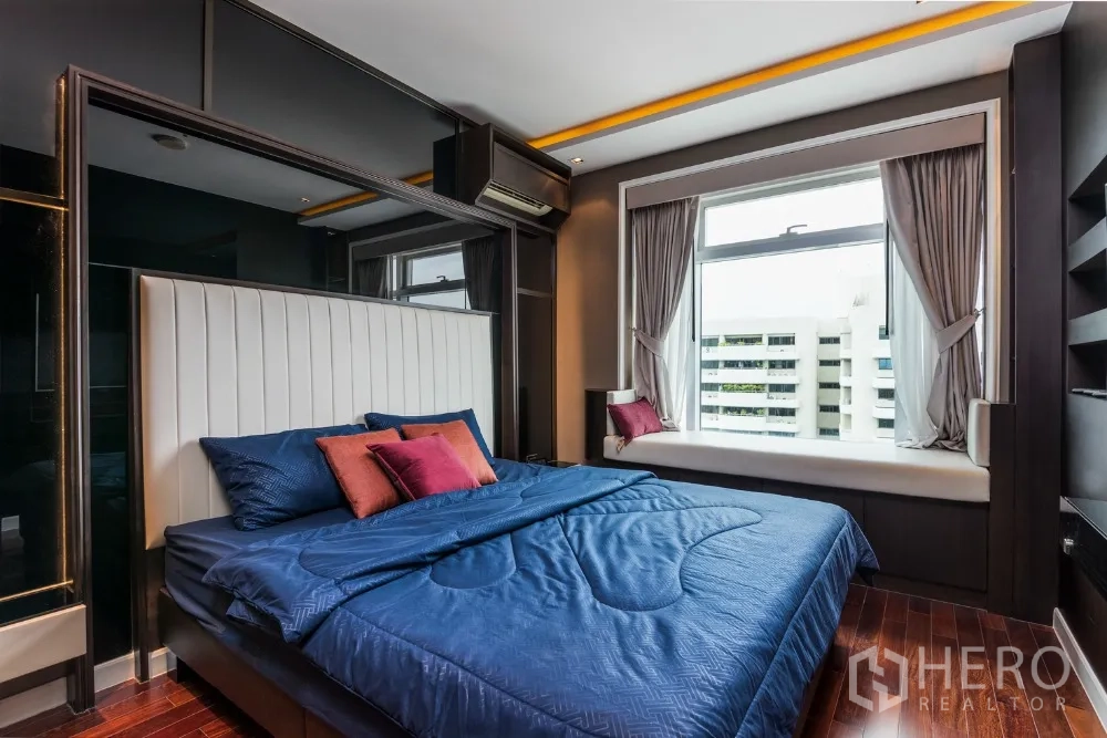 คอนโด ให้เช่าในRatchathewi, Bangkok - ห้องนอนใหญ่ ผ้าปูเตียงสีน้ำเงิน หัวเตียงบุผ้า และที่นั่งริมหน้าต่างขนาดใหญ่