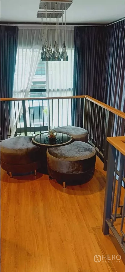 Detached House for rent or sale in Khan Na Yao, Bangkok - Upper landing lounge with pendant chandelier, round ottomans and floor-to-ceiling curtains.