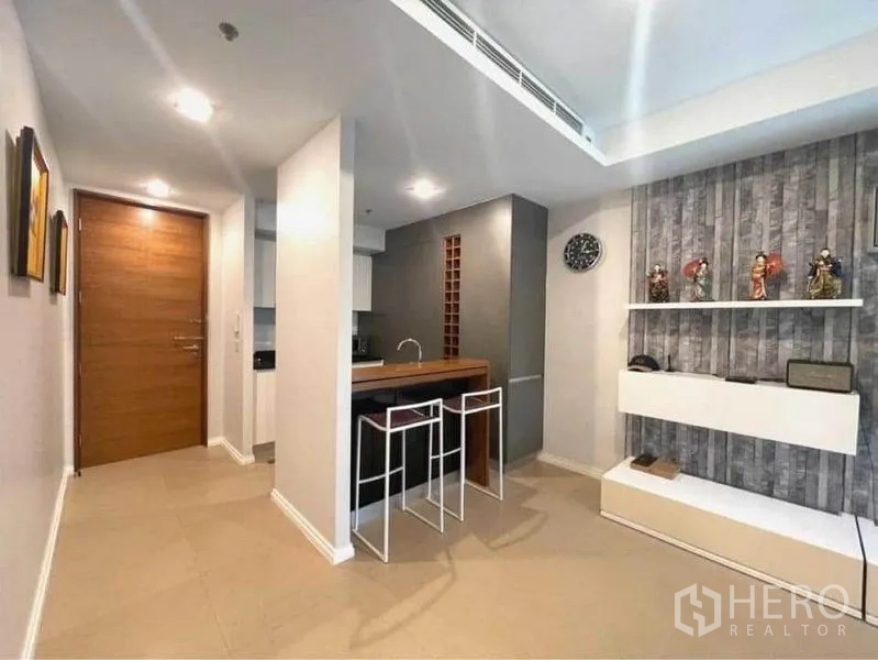 Condominium for rent in Khlong San, Bangkok - Entry and dining bar area with two stools and wall shelves beside the kitchen.