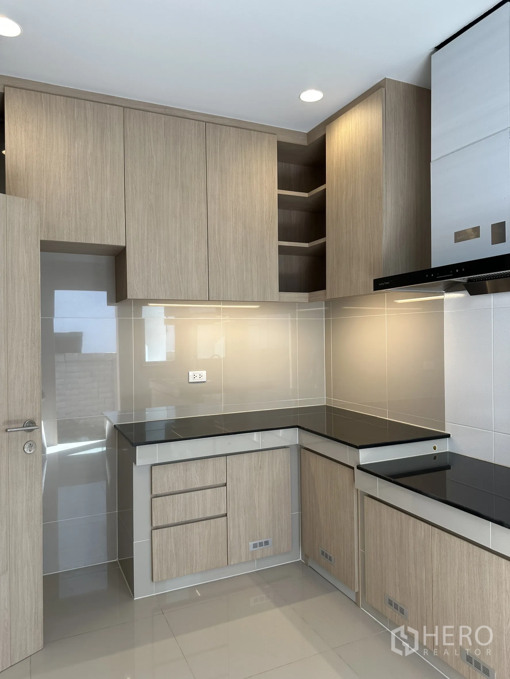 Detached House for sale in Lam Luk Ka, Pathum Thani - Thai kitchen with L-shaped wood cabinetry, black countertops and cooker hood.
