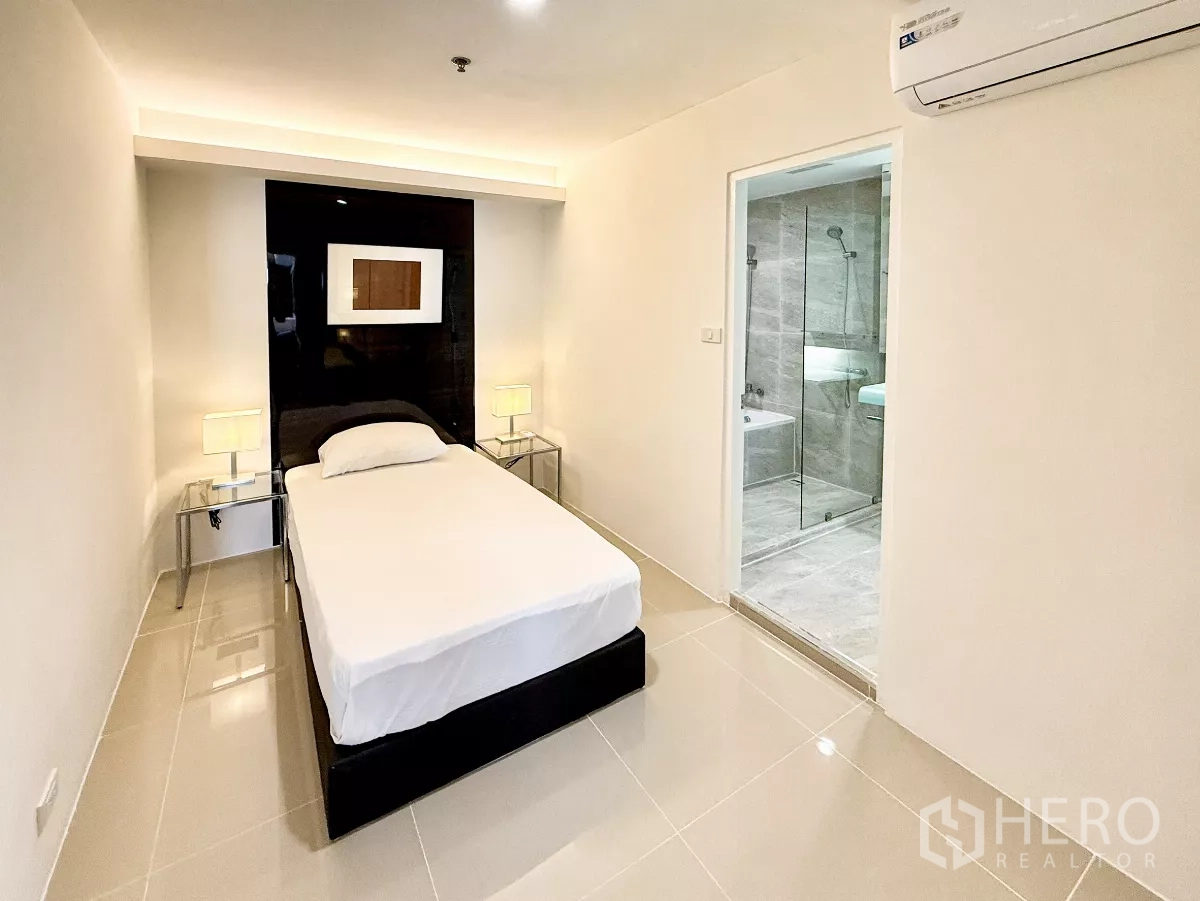 公寓 出租在Khlong Toei, Bangkok - 舒适单人卧室，床头灯并直通瓷砖浴室。