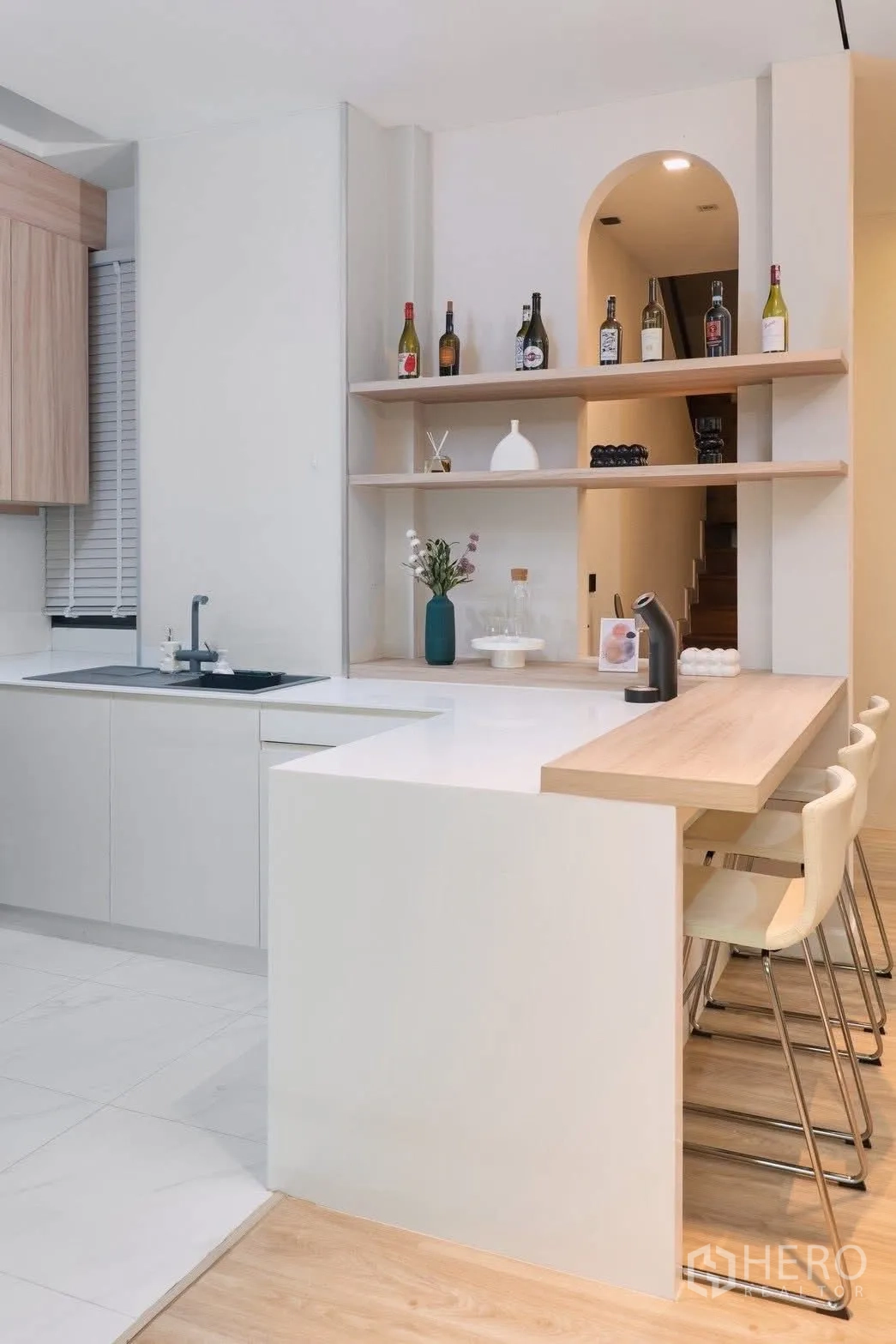 独栋房屋 for rent in Phra Khanong, Bangkok - 厨房与吧台，白色台面、木质置物架，后方可见楼梯。