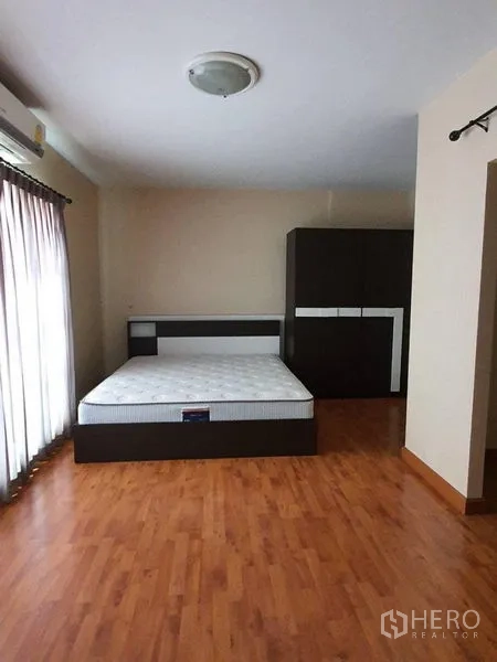 Townhouse for rent in Bueng Kum, Bangkok - Spacious bedroom featuring a double bed, dark wardrobe, and warm wood floors.