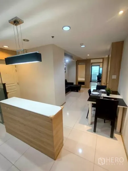 Condominium for rent in Khlong Toei, Bangkok - Entrance hall with pendant lighting, a compact breakfast bar, and a view toward the living and dining space in the condominium.