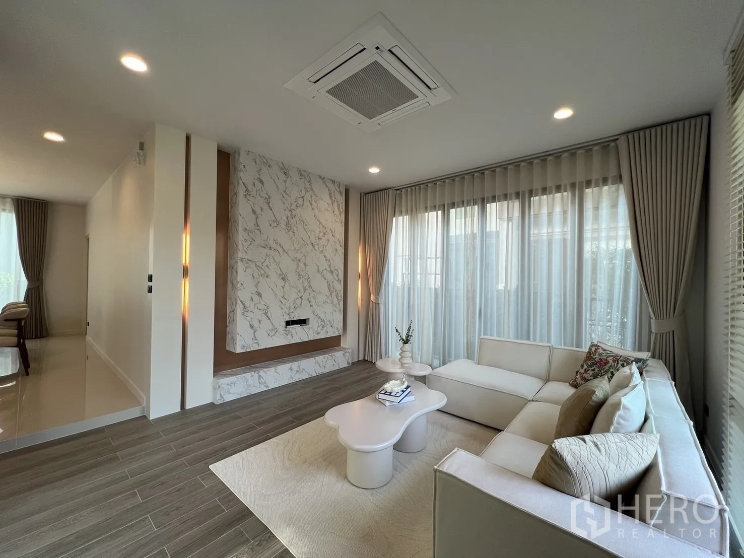 独立式住宅 出租或出售在Bang Kapi, Bangkok - 采光充足的客厅，L形沙发、大理石背景墙与纱帘。