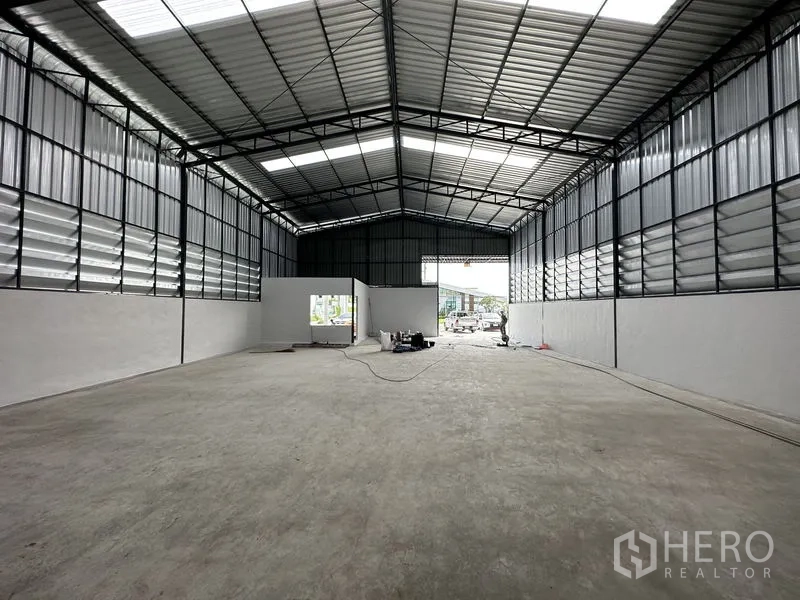 货栈 出租在Lam Luk Ka, Pathum Thani - 室内朝向宽阔装卸口的视角，耐磨混凝土地面与电力点清晰可见。