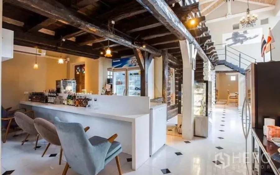 Retail Space for rent in Khlong Toei, Bangkok - Double-height retail interior with white bar counter, exposed dark timber beams and pendant lights.