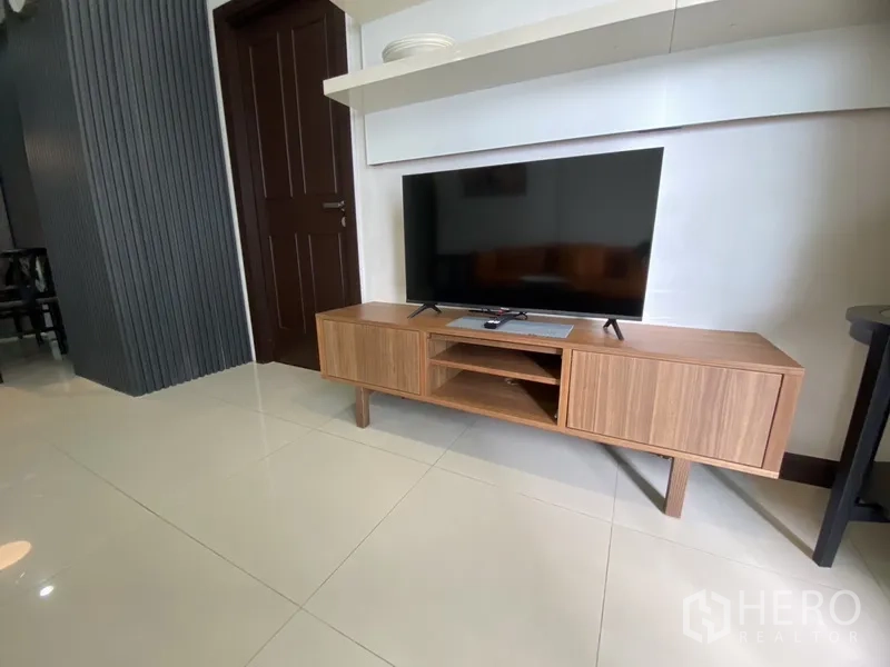 公寓 出租在Watthana, Bangkok - 木质电视柜上摆放平板电视，上方有悬浮层板。