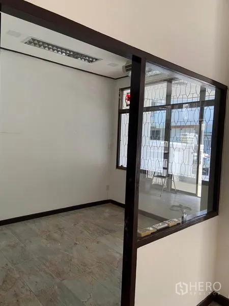联排别墅 出租在Khlong Toei, Bangkok - 带玻璃隔断的小房间，白色墙面、瓷砖地面与带花纹防盗窗的窗户。