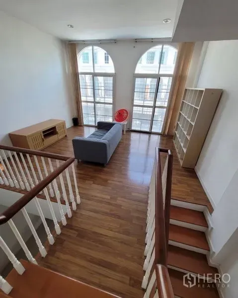 Townhouse for sale in Bang Kapi, Bangkok - Upper lounge with tall arched glazing, wood floors and stair landing.