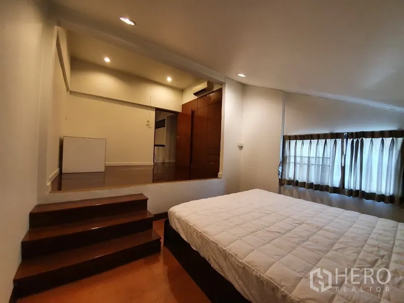 独立式住宅 出租在Phra Khanong, Bangkok - 卧室带台阶抬高区，内置衣柜、空调与窗帘。