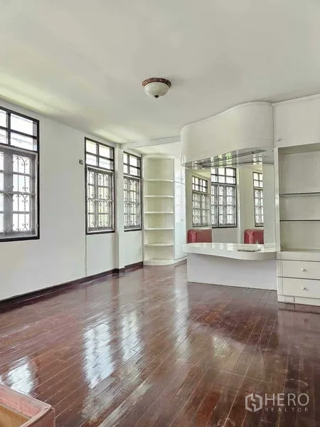 Detached House for sale in Saphan Sung, Bangkok - Upstairs bedroom with polished wooden flooring, built-in vanity and shelving, and multiple windows.