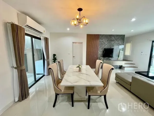 联排别墅 出租在Bang Phli, Samut Prakan - 餐区设大理石台面餐桌与吊灯，旁边是客厅与阳台门。