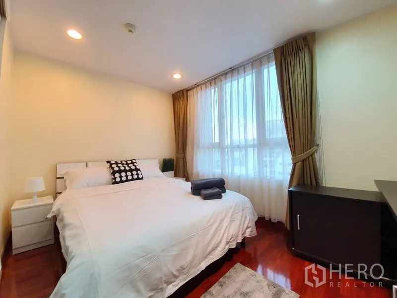 คอนโด ให้เช่าหรือขายในPathum Wan, Bangkok - ห้องนอนที่สองอบอุ่น มีโต๊ะข้างเตียง แสงไฟนุ่มและผ้าม่านโปร่ง